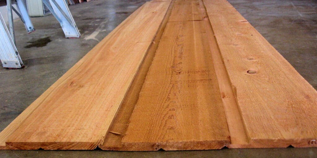 Cedar tongue and groove siding boards stacked flat, with smooth finished fronts and rough backs