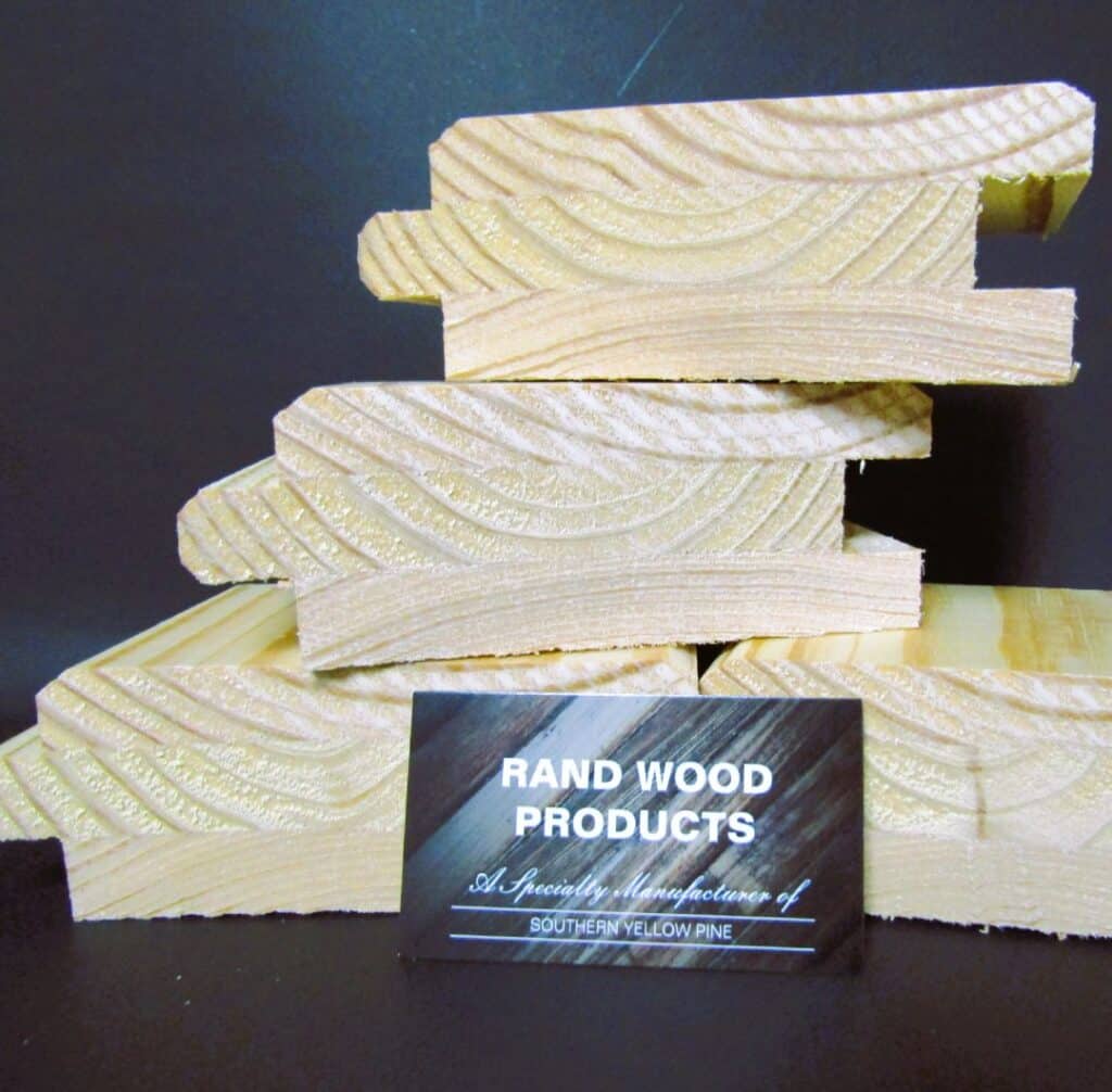 Stacked cut sections of specialty-milled Southern Yellow Pine tongue-and-groove boards with visible grain patterns, displayed with a Rand Wood Products business card in front